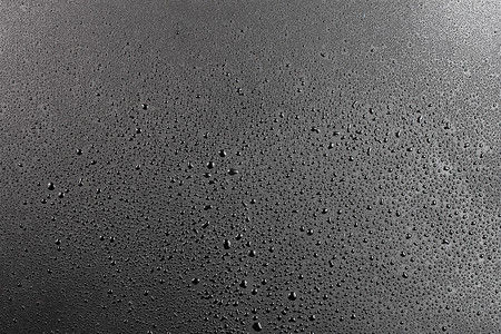下雨图片摄影照片_抽象平黑色疏水表面宏观背景上的水滴