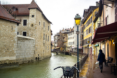 法国安纳西 — 2019年4月3日：老城区的蒂乌克斯河堤防，在雨天环绕着位于河中的一座中世纪宫殿 — 伊尔宫