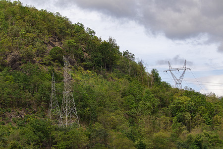高压电塔和输电线的图像有天空和山背景。