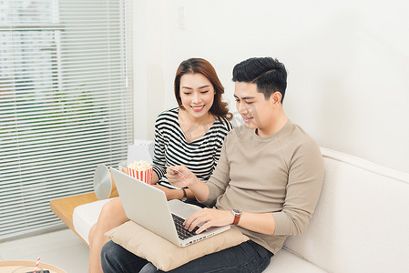 亚洲年轻夫妇使用笔记本电脑购买电影票在线支付