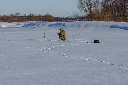 阳光明媚的日子里，钓鱼者在冰上钓鱼