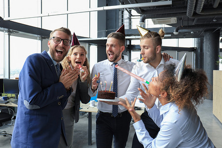 带着生日蛋糕的快乐商业团队在办公室聚会上向同事致意
