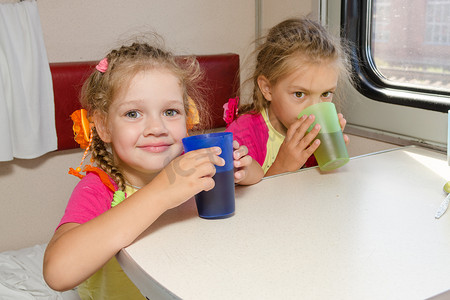 火车上的两个小姐妹在二等车厢下面的桌子上喝茶
