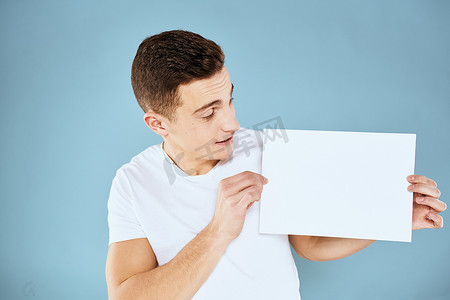 一个穿白色 T 恤的男人手里拿着一张纸，情绪是蓝色背景的裁剪视图 Copy Space