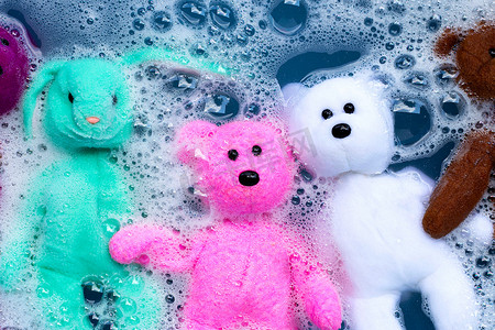 将带有玩具泰迪熊的兔子娃娃浸泡在洗衣粉水中
