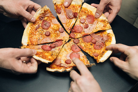 男性的手从送餐中取出披萨片、奶酪、西红柿和火腿。