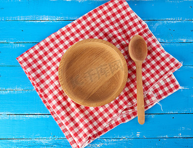 红白色纺织餐巾上的空圆形木盘和勺子