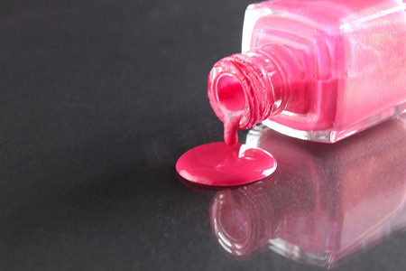 粉色指甲油从黑色背景的瓶子里倒出来，上面有文字的复制空间