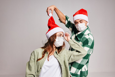戴着圣诞老人帽子的男人和女人圣诞节有趣的医用口罩工作室