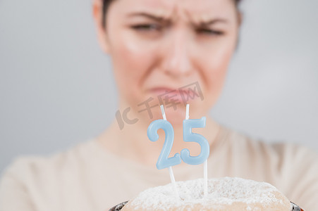 不幸的女人拿着一个点着蜡烛的蛋糕庆祝她的 25 岁生日。