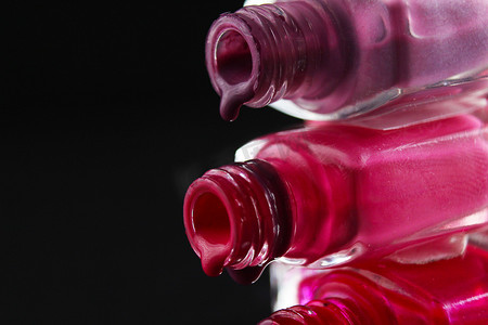 美容背景保护指甲油从罐装紫色红色勃艮第粉红色的小瓶中倒出，从侧面特写