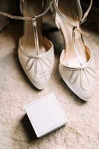 女式白鞋和石头质地的戒指盒。