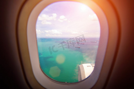 从飞机窗口到大海和阳光下的船只的美丽景色。