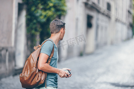 带智能手机的白人男孩在欧洲街头行走