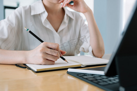 特写女性与她的老板或老师在线交流，并在家庭办公室的文案中做笔记