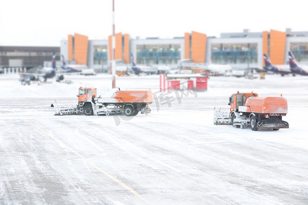 在暴风雪期间，除雪机从机场的跑道和道路上除雪，透过窗户看