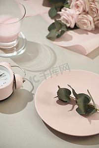 女士用品摄影照片_桌上摆着一束粉红玫瑰、盘子和草莓牛奶的女士用品
