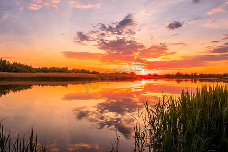 春季或初夏傍晚，池塘或湖泊上方美丽的日落或日出的风景。