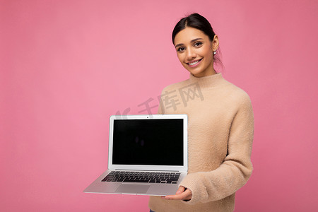 照片中，美丽的年轻女子拿着电脑笔记本电脑，看着彩色背景中突显的相机