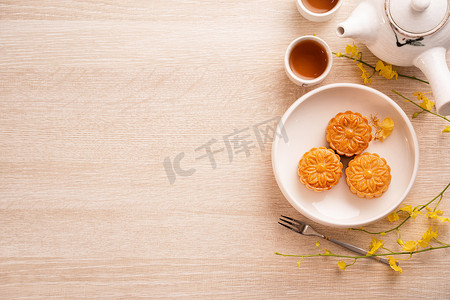 中中秋节摄影照片_明亮的木桌上有茶的月饼，中秋节传统食品布局设计的节日概念，顶视图，平躺，复制空间。