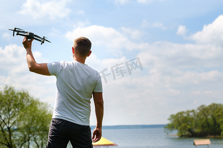 一个手里拿着飞行器的人，在大自然中升向天空。发射无人机