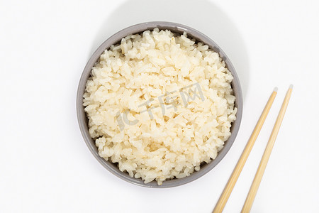 在碗的煮熟的米饭有在白色背景的筷子。