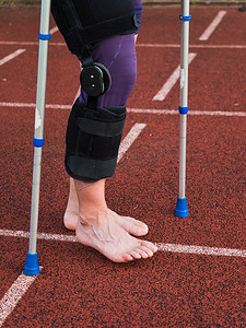 残奥会领跑摄影照片_赛后受伤的跑者拄着拐杖在赛道上行走