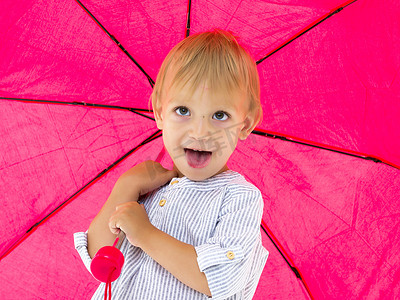 一个可爱的小男孩躲在伞下。