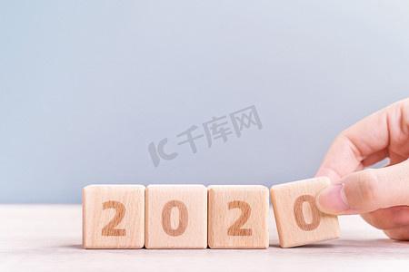 摘要2020年和2019年新年倒计时设计概念-妇女在木桌和蓝色背景上拿着木块立方体，特写，复制空间。