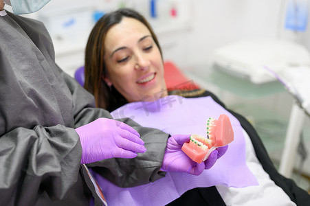 牙医向患者展示正畸牙齿模型，向患者解释牙科诊所的正畸治疗。