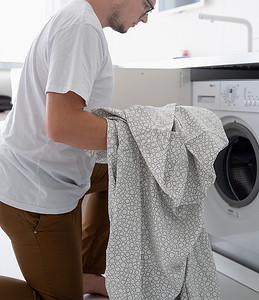年轻人把衣服放进洗衣机