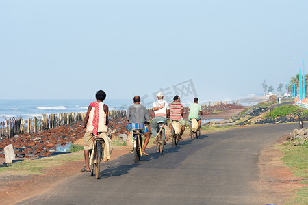 村民摄影照片_偏远沿海地区的一小群青壮年村民骑着自行车下班回家。