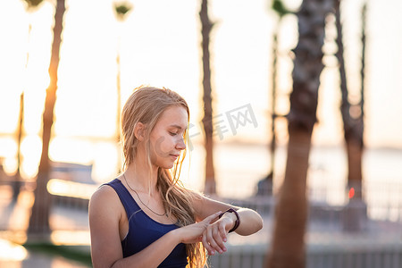 年轻女孩在日落日出时在海滨线上检查脉搏锻炼。