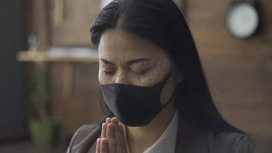 workwear摄影照片_戴面具的亚洲妇女在流行病期间孤立地祈祷