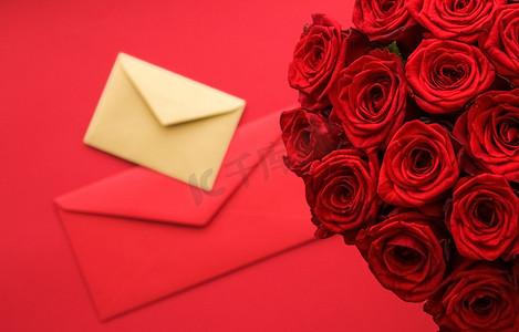 信封书信摄影照片_情人节情书和鲜花递送服务、豪华红玫瑰花束和红色背景的卡片信封