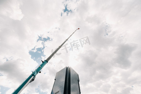 一台大型蓝色卡车起重机在一座大型现代建筑附近的工地上准备就绪。