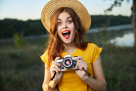 惊讶的女人与相机黄色 T 恤帽夏季自然生活方式