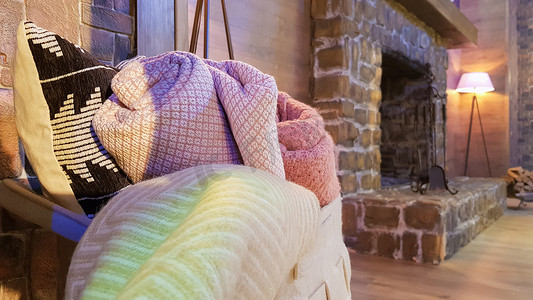 针织和温暖的毯子折叠起来放在壁炉旁的柳条篮子里。