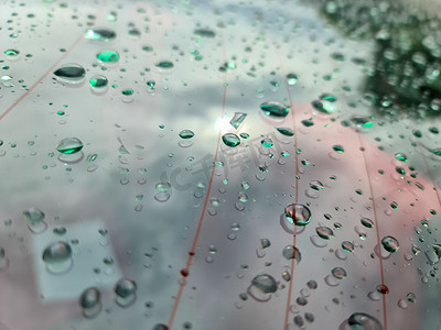 在特写视图中，雨滴落在黑色金属汽车表面上。