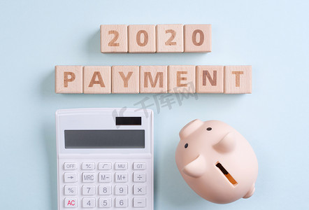 钱几何摄影照片_摘要2020年财务目标设计概念 — 蓝色桌子背景上的几何木块立方体，带存钱罐、顶视图、平躺、复制空间。