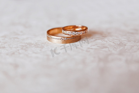 金色结婚戒指与白色图案背景上的钻石。