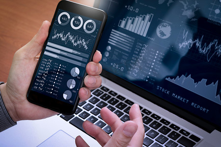 投资者使用商业智能 (BI) 和关键绩效指标 (KPI) 分析股市报告和财务仪表板。商人使用智能手机和笔记本电脑。