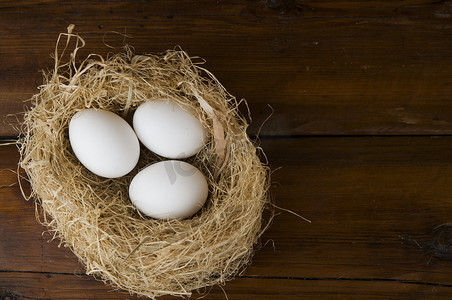 木桌上的巢里有白色的鸡蛋，有复制空间