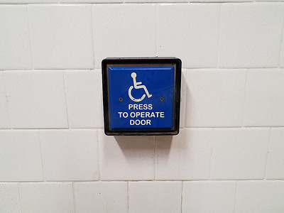 蓝色按下以操作白墙上的门轮椅按钮