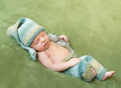 可爱的内裤摄影照片_戴着帽子和内裤的可爱新生儿蜷缩着睡觉