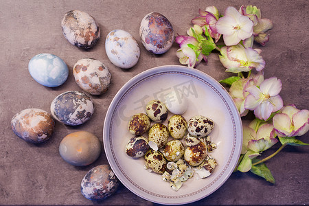 手绘彩色鲜花摄影照片_天然彩色复活节彩蛋，带洋葱皮，在混凝土背景上手绘鲜花