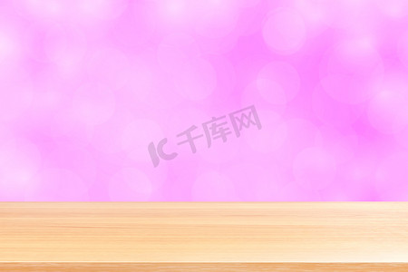 渐变粉红背景摄影照片_模糊的散景软粉色渐变背景上的空木桌地板，粉红色散景彩色浅色上空的木板，彩色散景灯渐变软用于横幅广告产品
