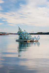玻璃风建筑摄影照片_奥斯陆 - 2011 年 5 月 4 日。“她的谎言”是一座漂浮的玻璃和钢结构建筑的名称，该建筑随风和潮汐而转动，由莫妮卡·邦维奇尼 (Monica Bonvicini) 设计