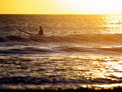 日落时分坐在海里的冲浪者