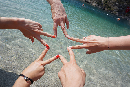 五只手在大海面前通过手指连接组成一个星形。
